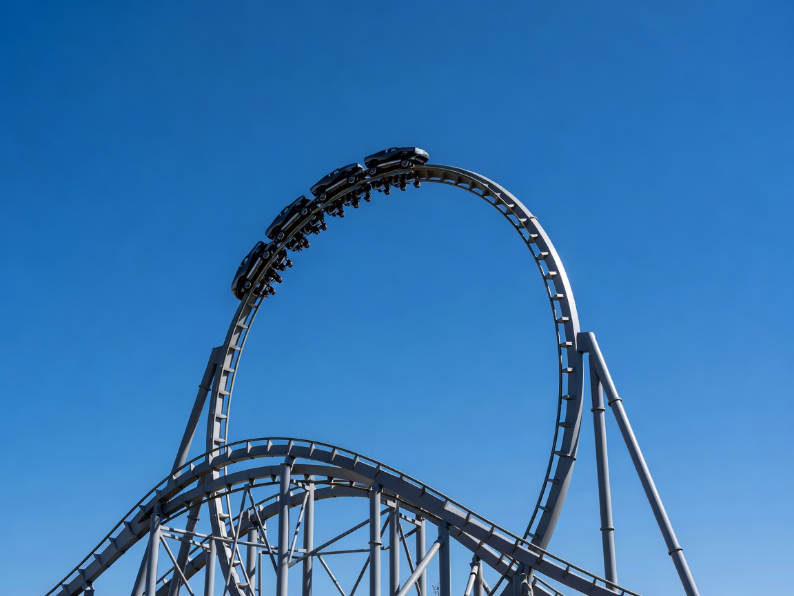 Theme park roller coaster track with looping element against blue sky